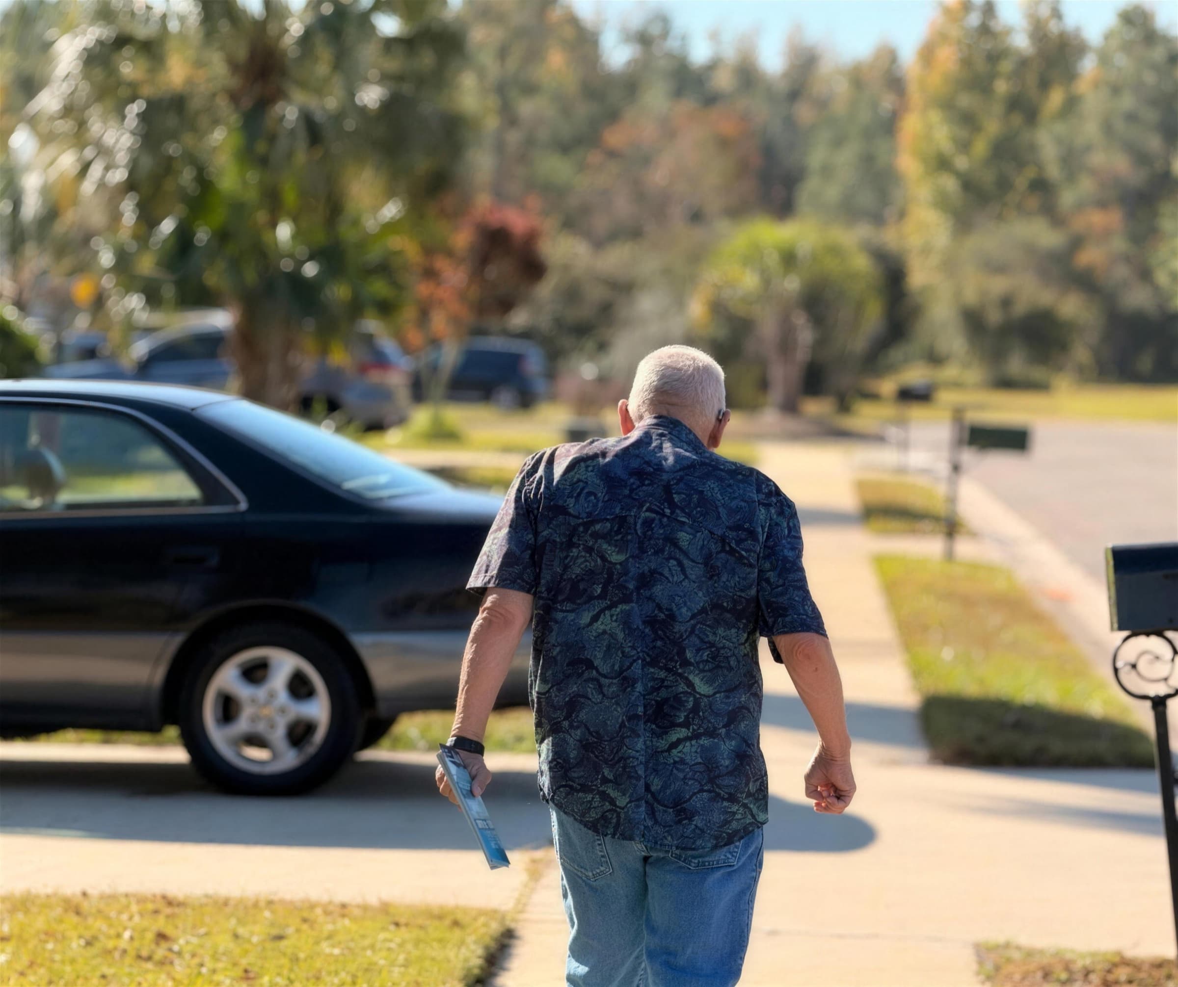 A church member walking up a driveway to visit a home, tract in hand