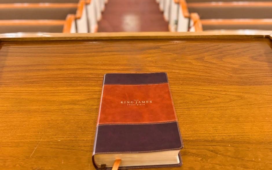 A King James Bible resting on a pew back in the empty auditorium